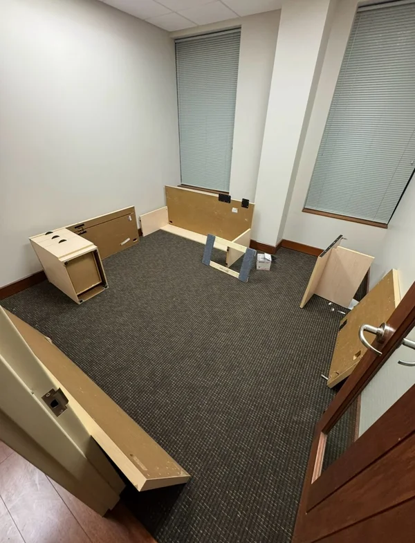 Disassembled desk panels and supports arranged around an office