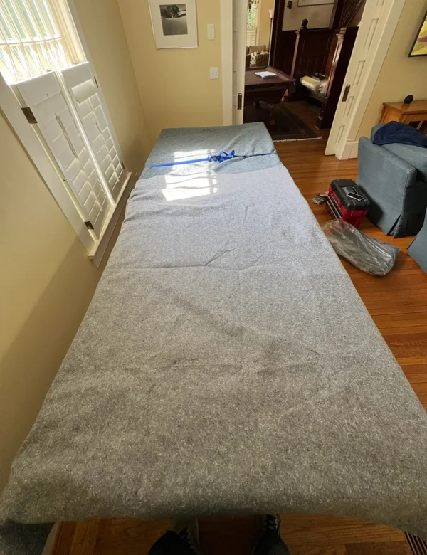 A large tabletop covered with a moving blanket and secured with a strap